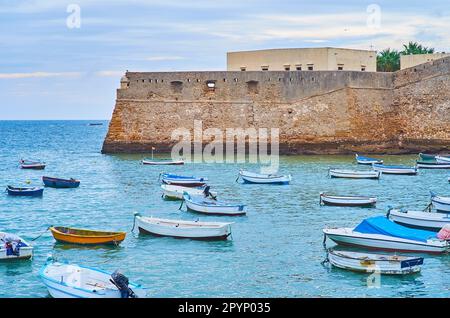 Le bastion médiéval en pierre du château de Santa Catalina avec de petits bateaux de pêche en premier plan, Cadix, Espagne Banque D'Images