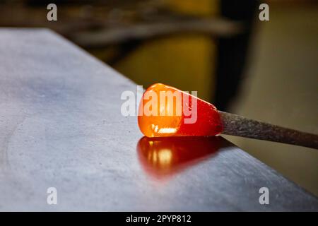 Un souffleur en verre de Murano contient une sculpture de cheval en verre chaud rouge Banque D'Images