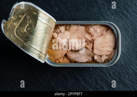 Boîte ouverte avec foie de morue sur fond noir, gros plan, vue de dessus Banque D'Images