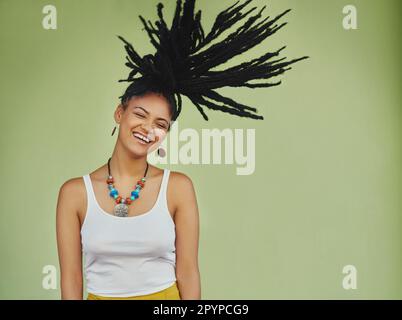 Laissez vos cheveux parler. Photo en studio d'une jeune femme attirante qui jette ses cheveux sur un fond vert. Banque D'Images