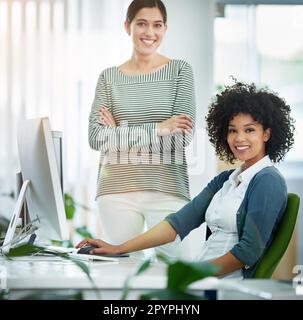 Nous avons fait passer la conception au niveau supérieur. Portrait de deux jeunes designers souriants travaillant sur un ordinateur dans un bureau moderne. Banque D'Images