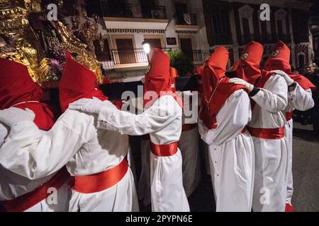 Nazarenos portant des capots rouges portent une plate-forme massive avec une statue de Jésus-Christ pendant la procession silencieuse de minuit commençant le Vendredi Saint à la semaine Sainte ou Semana Santa, 6 avril 2023 à Ronda, Espagne. Ronda, établie pour la première fois au 6th siècle avant Jésus-Christ, organise des processions de la semaine Sainte depuis plus de 500 ans. Banque D'Images