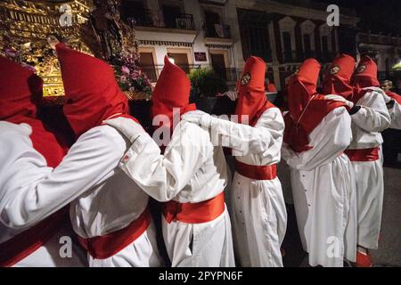 Nazarenos portant des capots rouges portent une plate-forme massive avec une statue de Jésus-Christ pendant la procession silencieuse de minuit commençant le Vendredi Saint à la semaine Sainte ou Semana Santa, 6 avril 2023 à Ronda, Espagne. Ronda, établie pour la première fois au 6th siècle avant Jésus-Christ, organise des processions de la semaine Sainte depuis plus de 500 ans. Banque D'Images