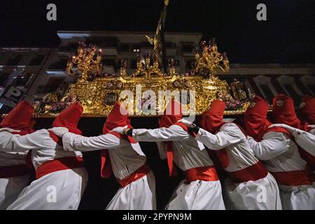 Nazarenos portant des capots rouges portent une plate-forme massive avec une statue de Jésus-Christ pendant la procession silencieuse de minuit commençant le Vendredi Saint à la semaine Sainte ou Semana Santa, 6 avril 2023 à Ronda, Espagne. Ronda, établie pour la première fois au 6th siècle avant Jésus-Christ, organise des processions de la semaine Sainte depuis plus de 500 ans. Banque D'Images