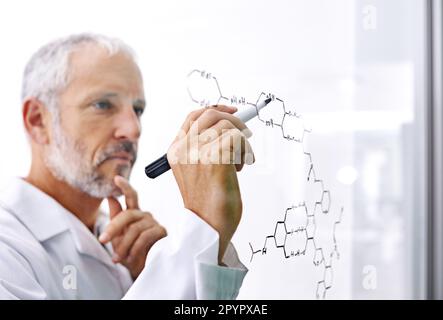 HES faisant des recherches de pointe. un scientifique mâle mature dessinant une structure moléculaire sur une surface en verre. Banque D'Images