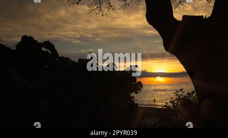 Une personne seule bénéficie d'un spectaculaire coucher de soleil le long de la côte à Kaanapali, à environ huit kilomètres au nord de Lahaina, Maui. Banque D'Images