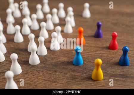 Pions colorés sur une table en bois. Concept d'inclusion sociale Banque D'Images