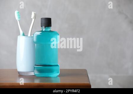 Bouteille de rince-bouche et brosses à dents sur une table en bois, espace pour le texte Banque D'Images