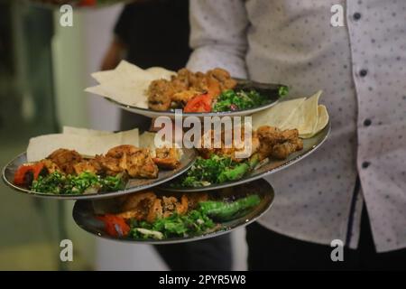 Une assiette avec un shish et un kebab adana dans les mains d'un gros plan de cuisson Banque D'Images