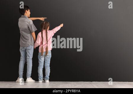 Petits enfants avec dessin de craie sur tableau noir, vue arrière Banque D'Images