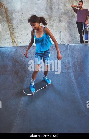 Agir comme une dame, skate comme un patron. une jeune femme qui fait des tours sur son skateboard au skate park. Banque D'Images