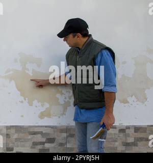 Image d'un ingénieur de construction illustrant les dommages causés à un mur de briques par des problèmes d'humidité. Réparation en raison de l'humidité qui monte Banque D'Images