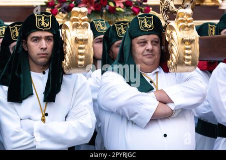 Nazarenos portant des chapeaux verts porte une plate-forme massive avec une statue de Jésus-Christ et les Romains dans une procession pendant la semaine Sainte ou Santa Semana, 5 avril 2023 à Ronda, Espagne. Ronda, établie pour la première fois au 6th siècle avant Jésus-Christ, organise des processions de la semaine Sainte depuis plus de 500 ans. Banque D'Images