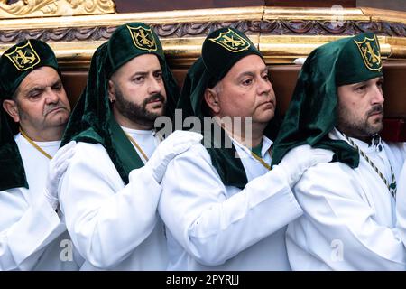 Nazarenos portant des chapeaux verts porte une plate-forme massive avec une statue de Jésus-Christ et les Romains dans une procession pendant la semaine Sainte ou Santa Semana, 5 avril 2023 à Ronda, Espagne. Ronda, établie pour la première fois au 6th siècle avant Jésus-Christ, organise des processions de la semaine Sainte depuis plus de 500 ans. Banque D'Images