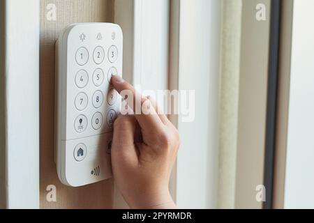 Les mains d'un jeune enfant entrent le code à une alarme de sécurité à domicile sur un clavier mural Banque D'Images