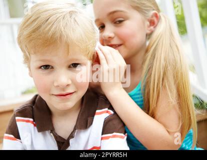 Laissez-moi vous dire un secret... Un petit garçon mignon écoutant sa sœur chuchoter dans son oreille. Banque D'Images