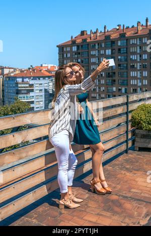 Deux amies emportant un selfie dans la ville sur le toit, un jour d'été Banque D'Images