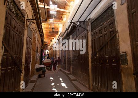 Fès, Maroc 2022: Rues étroites historiques et traditionnelles de Fès el-Bali, la vieille médina, avec des boutiques du souk (suq) et des gens Banque D'Images