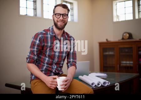 Obtenir un apport en caféine avant le début de la planification. Portrait d'un jeune architecte masculin ayant un café dans son bureau. Banque D'Images