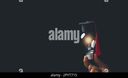 académie et succès de l'enseignement supérieur concept. homme d'affaires tenant une ampoule électrique brillante avec un capuchon de degré sur fond noir. edu Banque D'Images