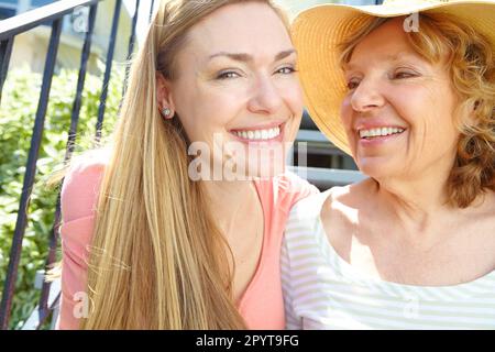 Passer du temps avec la mère au soleil d'été. Une belle femme mûre souriant largement tout en prenant du temps avec sa mère âgée. Banque D'Images