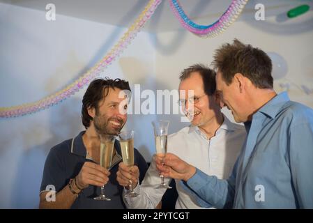 Des hommes qui font des toasts de fête avec du vin mousseux Banque D'Images