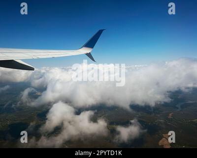 Vue aérienne d'une aile d'avion sur fond de nuages blancs moelleux dans un ciel bleu. Banque D'Images