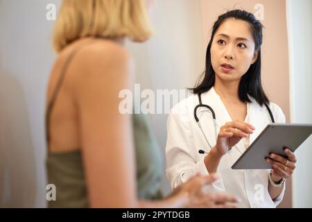 Femme médecin tenant un Tablet PC tout en discutant avec le patient Banque D'Images