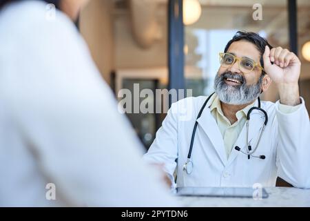 Joyeux médecin de sexe masculin portant des lunettes de vue regardant la patiente Banque D'Images
