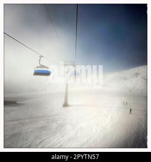 DE LA SÉRIE ADELBODEN téléphérique dans la neige en face du paysage viticole à Adelboden, Oberland bernois, canton de Berne, Suisse. La ville pittoresque d'Adelboden est une idylle suisse dans les Alpes bernoises, des sommets impressionnants, un paysage d'hiver unique, un domaine skiable populaire, des pâturages alpins, cascades jaillissantes, maisons en bois confortables. En raison du changement climatique et de moins en moins de neige, le complexe sportif classique d'hiver se réoriente et la saison estivale devient de plus en plus importante photo prise avec iPhone, application Hipstamatic. Banque D'Images