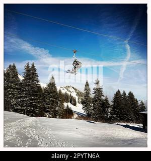 DE LA SÉRIE ADELBODEN téléphérique dans la neige en face du paysage viticole à Adelboden, Oberland bernois, canton de Berne, Suisse. La ville pittoresque d'Adelboden est une idylle suisse dans les Alpes bernoises, des sommets impressionnants, un paysage d'hiver unique, un domaine skiable populaire, des pâturages alpins, cascades jaillissantes, maisons en bois confortables. En raison du changement climatique et de moins en moins de neige, le complexe sportif classique d'hiver se réoriente et la saison estivale devient de plus en plus importante photo prise avec iPhone, application Hipstamatic. Banque D'Images