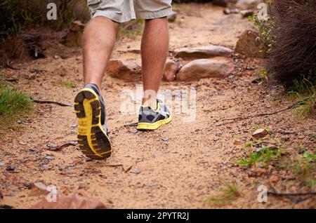 Chewing up the trail. a mans legs as he hikes up a rocky trail. Stock Photo