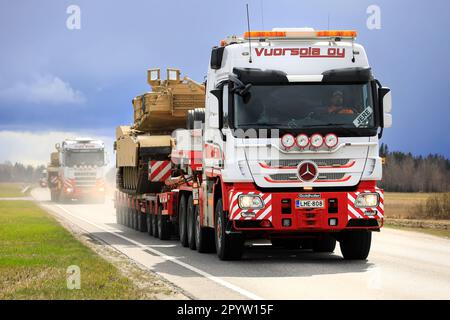 Mercedes-Benz transporte le char militaire American M1 Abrams sur semi-remorque à chargeur bas. Convoi de 3 grands transports. Aura, Finlande. 28 avril 2023. Banque D'Images