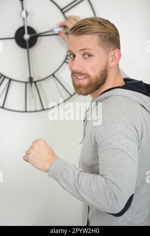 homme changeant l'heure sur une belle horloge murale Banque D'Images