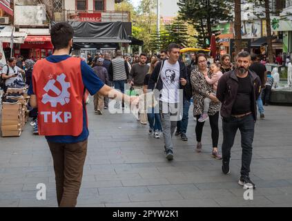 Dans une rue commerçante animée d'Antalya, en Turquie (Turkiye), un membre du Parti communiste turc (TKP) étend son bras pour distribuer la feuille électorale Banque D'Images