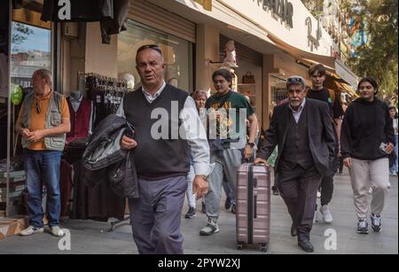 Un homme âgé vêtu d'un costume pousse une valise le long de laquelle d'autres Turcs marchent dans une rue commerçante animée d'Antalya, province d'Antalya, Turquie ( Banque D'Images