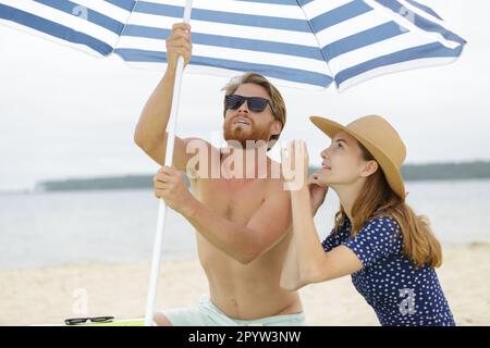 couple sur une plage sous un parapluie rouge Banque D'Images