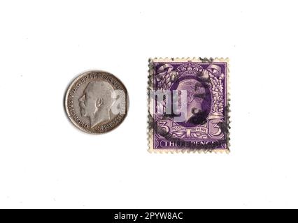 Pièce de Threepence et timbre du règne du roi George V isolé sur fond blanc. Banque D'Images