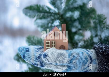 Un modèle d'une maison en bois écologique dans les mains sur un fond d'hiver.Le concept d'achat d'une maison de campagne, hypothèque immobilière Banque D'Images