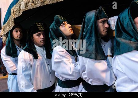 Nazarenos portant des chapeaux verts porte une plate-forme massive avec une statue de la Vierge Marie dans une procession pendant la semaine Sainte ou Santa Semana, 5 avril 2023 à Ronda, Espagne. Ronda, établie pour la première fois au 6th siècle avant Jésus-Christ, organise des processions de la semaine Sainte depuis plus de 500 ans. Banque D'Images