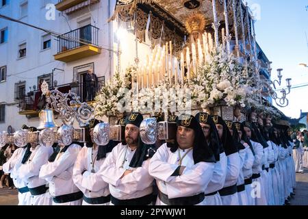 Nazarenos portant des chapeaux verts porte une plate-forme massive avec une statue de la Vierge Marie dans une procession pendant la semaine Sainte ou Santa Semana, 5 avril 2023 à Ronda, Espagne. Ronda, établie pour la première fois au 6th siècle avant Jésus-Christ, organise des processions de la semaine Sainte depuis plus de 500 ans. Banque D'Images