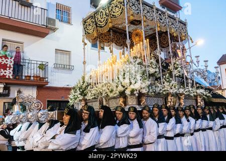 Nazarenos portant des chapeaux verts porte une plate-forme massive avec une statue de la Vierge Marie dans une procession pendant la semaine Sainte ou Santa Semana, 5 avril 2023 à Ronda, Espagne. Ronda, établie pour la première fois au 6th siècle avant Jésus-Christ, organise des processions de la semaine Sainte depuis plus de 500 ans. Banque D'Images