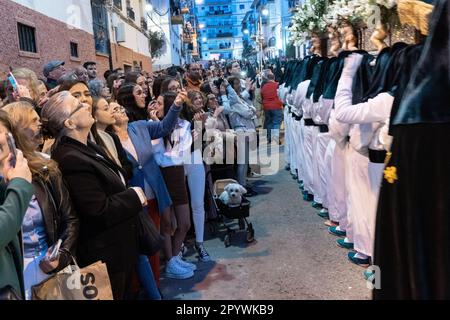 Les spectateurs regardent Nazarenos porter une plate-forme massive avec une statue de la Vierge Marie dans une procession pendant la semaine Sainte ou Santa Semana, 5 avril 2023 à Ronda, Espagne. Ronda, établie pour la première fois au 6th siècle avant Jésus-Christ, organise des processions de la semaine Sainte depuis plus de 500 ans. Banque D'Images