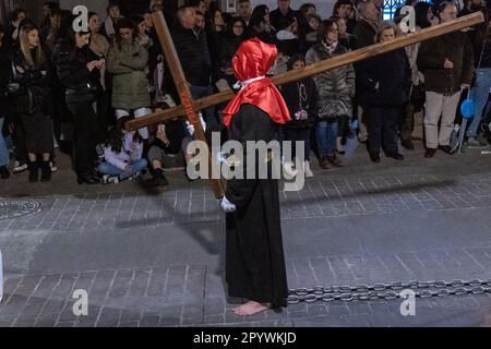 Un penitent à capuche marche pieds nus avec des chaînes comme il porte une croix en bois pendant la procession silencieuse de minuit marquant le Vendredi Saint à la semaine Sainte ou Semana Santa, 6 avril 2023 à Ronda, Espagne. Ronda, établie pour la première fois au 6th siècle avant Jésus-Christ, organise des processions de la semaine Sainte depuis plus de 500 ans. Banque D'Images