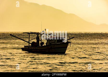 Chalutier en bois utilisé pour la pêche flottant sur la mer au coucher du soleil à Ilhabela sur la côte de Sao Paulo, Brésil, Brésil Banque D'Images