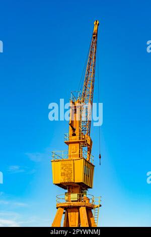 Grue jaune ancienne et obsolète sur la jetée du port éclairée par le soleil de l'après-midi avec le ciel bleu en arrière-plan., Brésil Banque D'Images