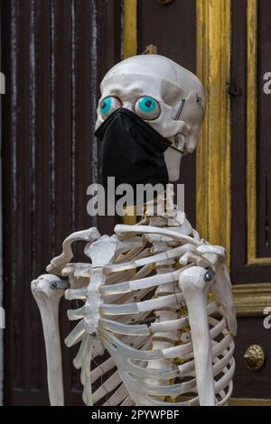 Bâle, Suisseladn – 26 octobre 2021 : un modèle de squelette portant un masque facial en face d'une entrée du musée pour rappeler aux visiteurs avec humour Banque D'Images
