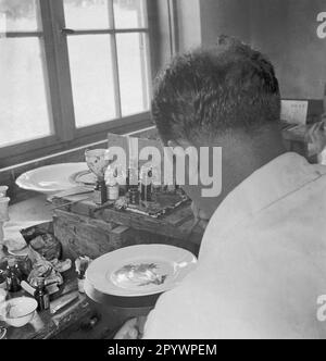 L'homme peint la porcelaine avec des fleurs sauvages. Photo non datée d'environ 1935 Banque D'Images