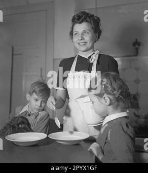 'Autre avec ses enfants et chien à la table à manger. Le chien est assis sur les genoux du fils. Scène de la série ''nous travaillons ensemble'. Le photographe accompagne les couples dans leurs occupations respectives. » Banque D'Images