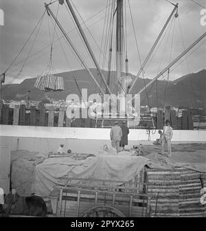 Les marchandises sont chargées sur un navire dans le port de Ponta Delgada. Le transport sur terre est effectué par le véhicule tiré à cheval sur la gauche. Photo non datée, probablement prise en 1930s. Banque D'Images